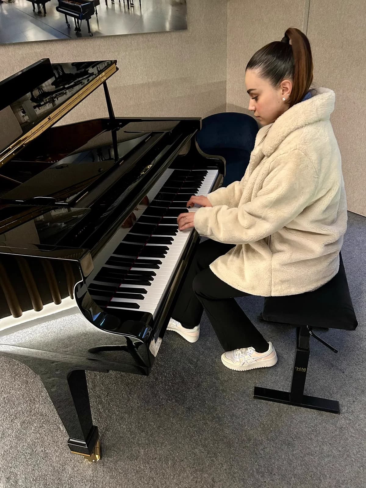 Inès joue sur un piano à queue, concentrée sur le clavier