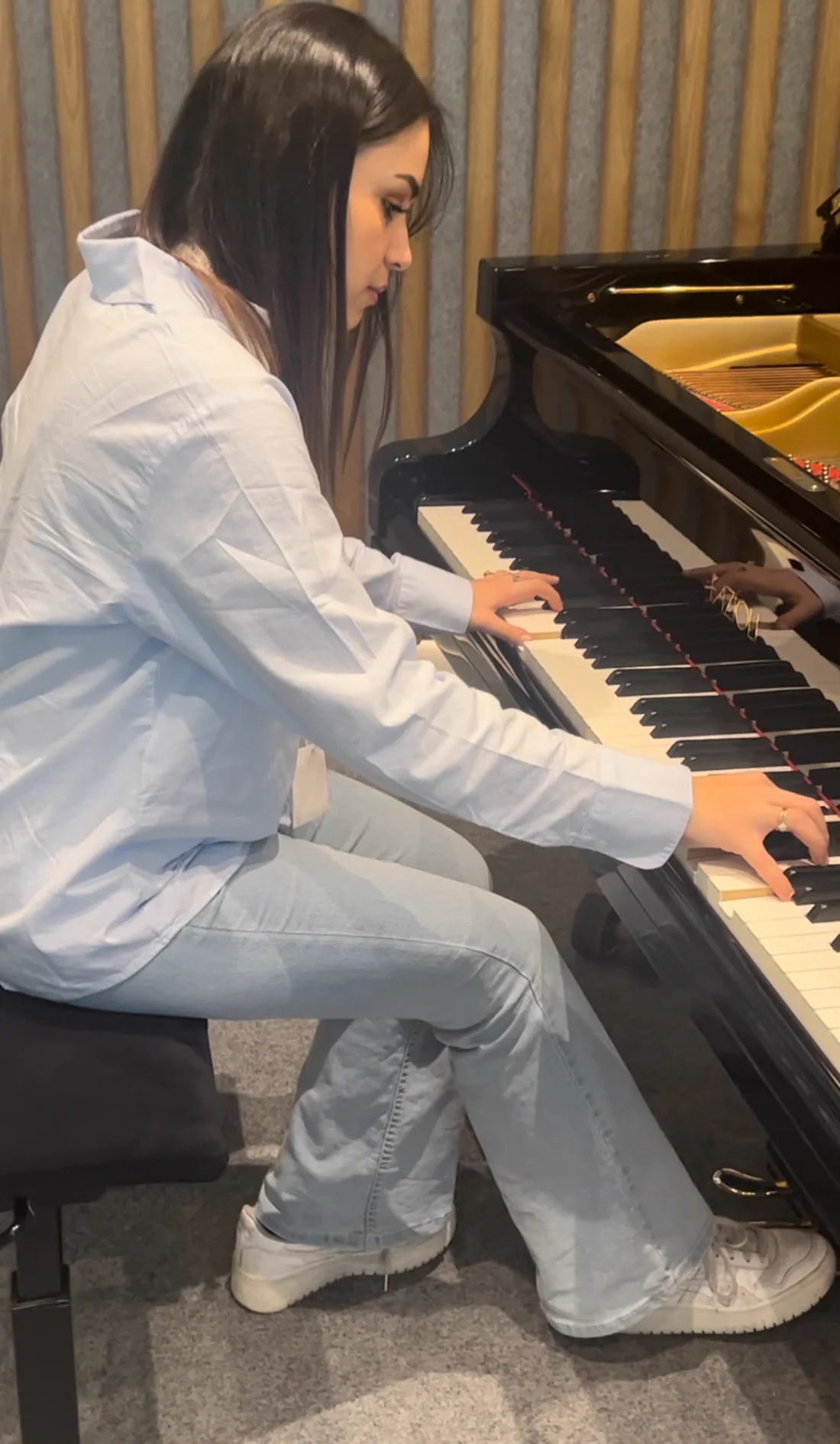 Inès joue du piano, les deux mains posées sur le clavier